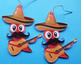 May include: A pair of red and black sombrero earrings with a cartoon character playing a guitar. The character has a mustache and big eyes.