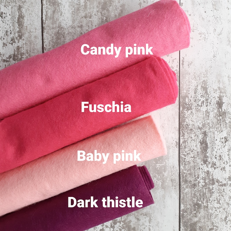 May include: Four rolls of felt fabric in different shades of pink and purple. The colors are labeled "Candy pink", "Fuschia", "Baby pink", and "Dark thistle".