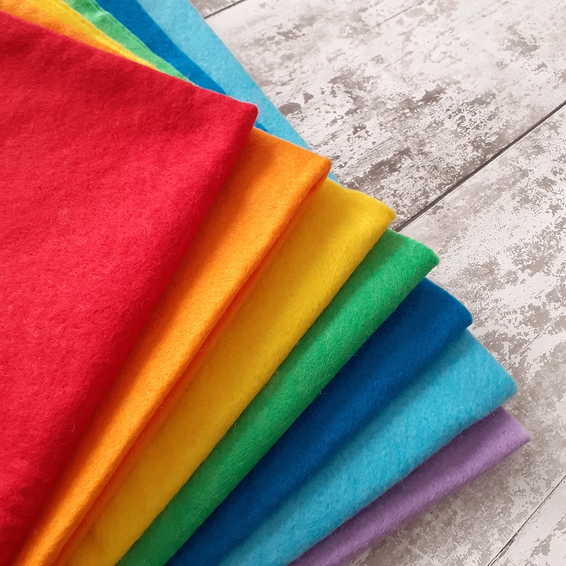 May include: A stack of felt fabric squares in rainbow colors, including red, orange, yellow, green, blue, light blue, and purple.