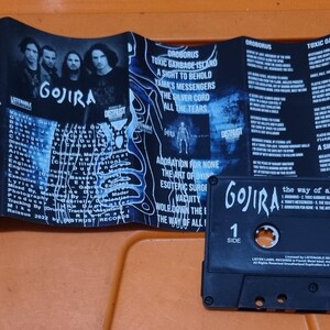 Pu&ograve; includere: Un nastro per cassette nero con il nome della band "GOJIRA" e il titolo dell'album "The way of all flesh" stampato sul lato anteriore. La cassetta &egrave; in una custodia di plastica trasparente con un'etichetta nera.
