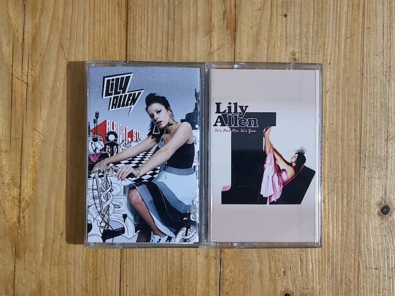 Może przedstawiać: Dwie kasety magnetofonowe z okładkami album&oacute;w Lily Allen. Jedna przedstawia kobietę w czarnym topie i sp&oacute;dnicy, druga kobietę w r&oacute;żowej sukience. Widoczne są tytuły album&oacute;w.
