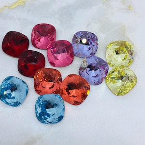 May include: Assortment of colorful square-shaped glass rhinestones. The rhinestones are in shades of red, pink, blue, yellow, and purple.