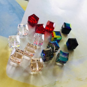 May include: Assortment of colourful glass beads in various shapes and sizes, including clear, red, black, and iridescent.