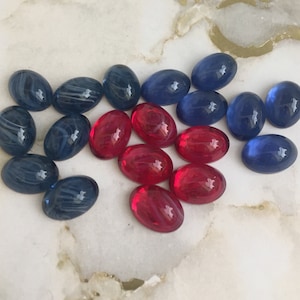 Op de afbeelding: Assortiment van ovale glazen cabochons in rood, blauw en wit. De cabochons hebben een geswirlde patroon.