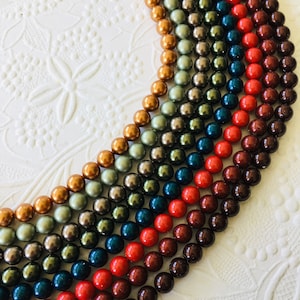 May include: A rainbow assortment of round, smooth, pearl-like beads in various shades of brown, red, blue, green, and gold.