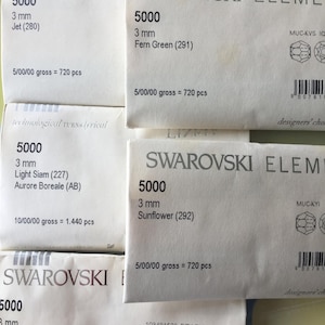 May include: Four packets of Swarovski Elements, each containing 5000 pieces of 3 mm crystals. The packets are labelled with the colour and code of the crystals. The colours are Jet (280), Fern Green (291), Light Siam (227), and Sunflower (292).