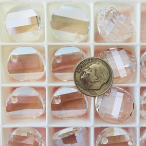 May include: A close-up of a white plastic container filled with clear glass beads. The beads are round and have a hole in the center. A US dime is included for scale.