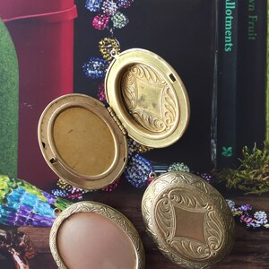 May include: Three gold oval locket pendants with intricate engraved designs. The lockets have a hinged opening and are perfect for holding a small photo or memento.