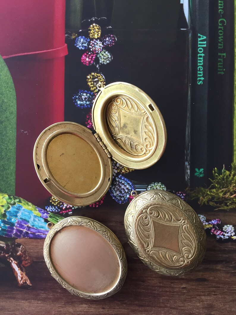 May include: Three gold oval locket pendants with intricate engraved designs. The lockets have a hinged opening and are perfect for holding a small photo or memento.