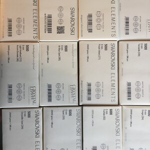 Peut inclure: Une collection de 10 bo&icirc;tes de Swarovski Elements, chacune contenant 5 000 cristaux de 8 mm de diff&eacute;rents coloris. Les bo&icirc;tes sont &eacute;tiquet&eacute;es avec le nom et le num&eacute;ro de la couleur, ainsi que la taille et la quantit&eacute; de cristaux.