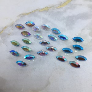 May include: Assortment of iridescent marquise-shaped rhinestones in various shades of blue, purple, and white.