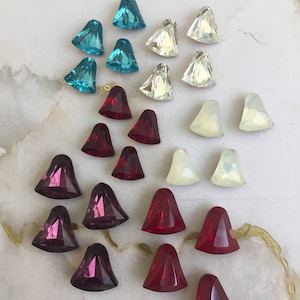 Puede incluir: Surtido de piedras de cristal de diferentes colores, incluyendo turquesa, rojo, morado y blanco. Las piedras tienen forma de lágrima con una punta.