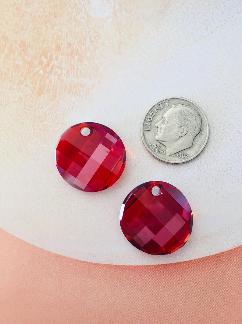 May include: Two red round crystal beads with a hole in the center. The beads are about the size of a US dime.