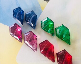 May include: Six diamond-shaped glass beads with swirling patterns. Two are blue, two are green, and two are pink.