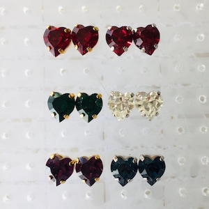Peut inclure: Six paires de boucles d'oreilles en forme de cœur avec des montures dorées. Les boucles d'oreilles sont en quatre couleurs : rouge, vert, blanc et bleu.