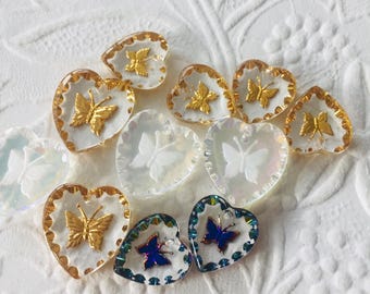 Puede incluir: Surtido de botones de vidrio en forma de corazón con diseños de mariposas. Algunos botones presentan mariposas doradas, mientras que otros tienen mariposas azules iridiscentes.
