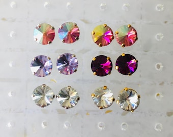 May include: Assortment of 10 pairs of small, round, iridescent earrings in various colors, including pink, purple, and clear. The earrings are displayed on a white background.