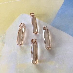 May include: Four clear glass prism pendants in a light peach color. The prisms are long and rectangular.