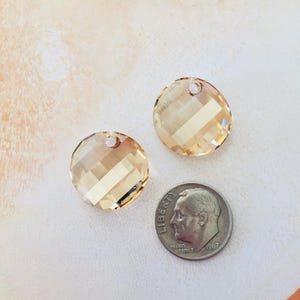 May include: Two round, faceted, light amber crystal charms with a hole for stringing. The charms are about the size of a dime.