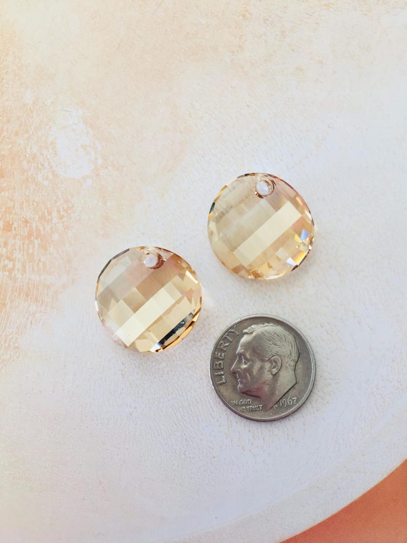 May include: Two round, faceted, light amber crystal charms with a hole for stringing. The charms are about the size of a dime.