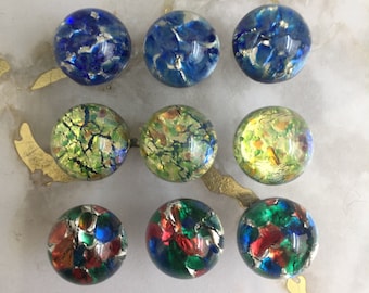 May include: Nine round glass marbles with a variety of colors and patterns. The marbles are iridescent and have a metallic sheen. The colors include blue, green, yellow, red, and gold.