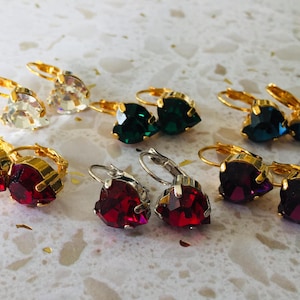 May include: Assortment of heart-shaped earrings with gold and silver settings. The earrings feature various colors, including clear, red, green, and blue.