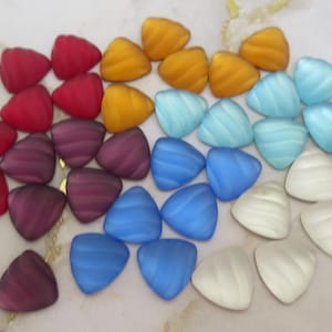 May include: A collection of colorful, triangular glass beads in a gradient of colors. The beads transition from red to purple, then to yellow, light blue, blue, and finally white. Each bead has a textured, swirled design.