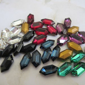 May include: Assortment of colorful glass gems in various shapes and sizes. The gems are in shades of red, blue, green, gold, and purple.