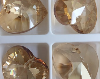 May include: Four gold-toned crystal heart-shaped pendants with faceted surfaces. The pendants have a hole at the top for stringing.