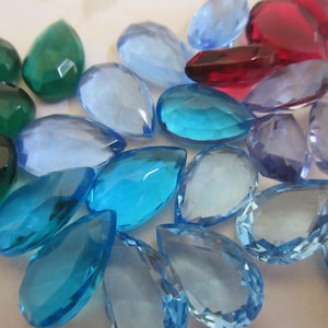 May include: Assortment of teardrop-shaped faceted glass beads in various shades of blue, green, purple, and red.