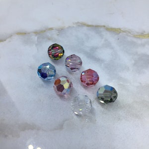 Peut inclure: Assortiment de huit perles de verre facett&eacute;es de diff&eacute;rentes couleurs, notamment transparentes, roses, bleues et iris&eacute;es.