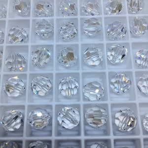 Peut inclure: Un r&eacute;cipient en plastique blanc rempli de perles de verre transparentes. Les perles sont rondes et ont un design facett&eacute;.
