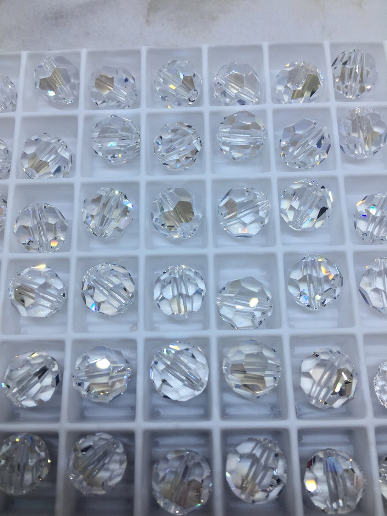 Peut inclure: Un r&eacute;cipient en plastique blanc rempli de perles de verre transparentes. Les perles sont rondes et ont un design facett&eacute;.