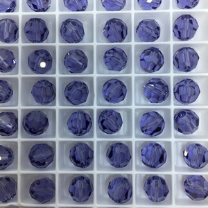 May include: A close-up view of a grid of small, round, purple glass beads. The beads are arranged in a grid pattern and are all the same size and shape.