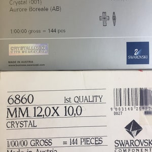May include: A white box with the text "6860 MM 12,0X 10,0 CRYSTAL 1/00/00 GROSS = 144 PIECES Made in Austria" and the logo "SWAROVSKI COMPONENT".