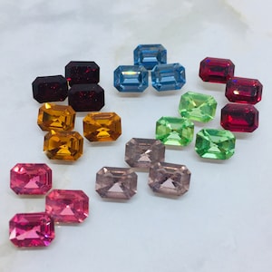 May include: Assortment of colorful, faceted, rectangular glass gems in various shades of red, blue, green, orange, pink, and gray.