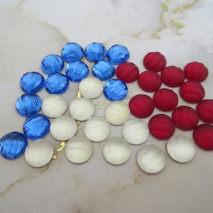 May include: Assortment of round glass cabochons in red, white and blue colours. The cabochons are arranged in a semi-circle pattern.