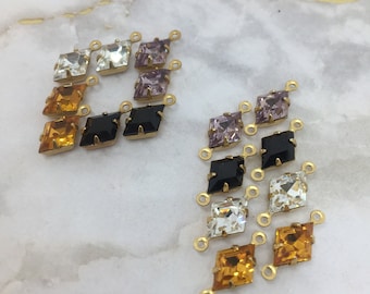 May include: A set of gold-toned metal connectors with various colored square rhinestones. The connectors are designed to be used in jewelry making.