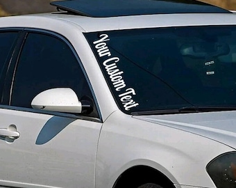 May include: White vinyl decal sticker for a car windshield. The sticker says "Your Custom Text" in a cursive font.