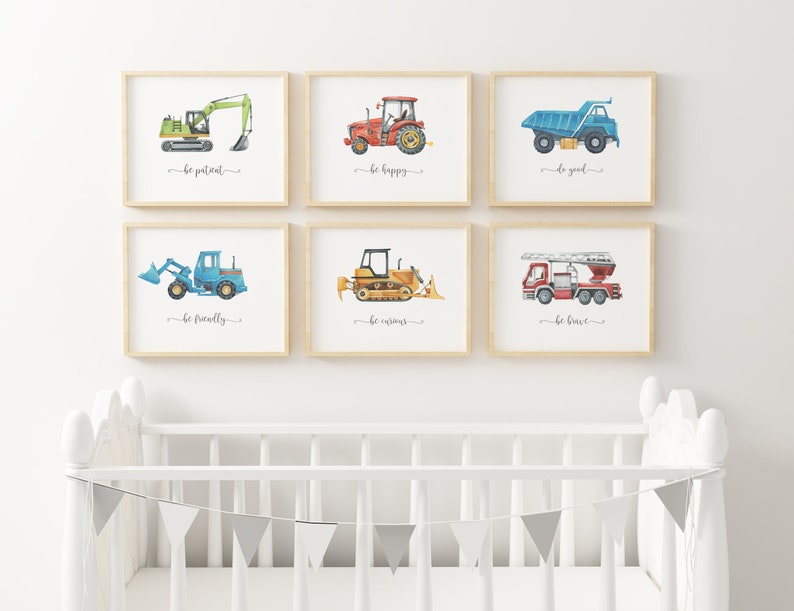 Op de afbeelding: Zes ingelijste prints met aquarel illustraties van bouwvoertuigen en inspirerende boodschappen. De prints tonen een groene graafmachine, een rode tractor, een blauwe kiepwagen, een blauwe graafmachine, een gele bulldozer en een rode brandweerwagen. Elke print heeft een andere boodschap, zoals "wees geduldig", "wees gelukkig", "wees goed", "wees vriendelijk", "wees nieuwsgierig" en "wees dapper".