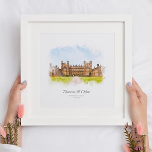 May include: A framed watercolor print of a stately building with a long driveway, under a blue and white sky. The print is in a white frame and includes the names "Thomas & Chloe" and the date "16.09.2023".