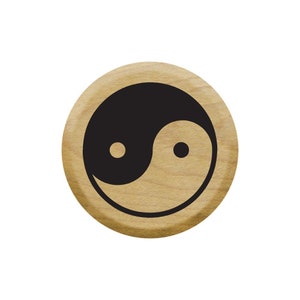 May include: A round wooden stamp with a black and white yin yang symbol.