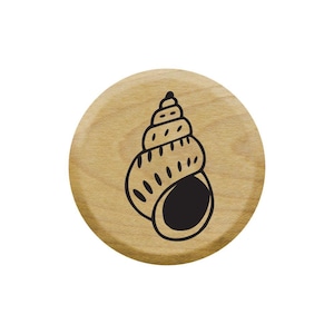 Pode incluir: Um carimbo de madeira com um contorno preto de uma concha. A concha é em forma de espiral com uma ponta pontiaguda.