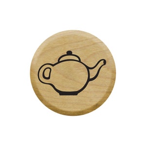 May include: A wooden circle with a black outline of a teapot on it.