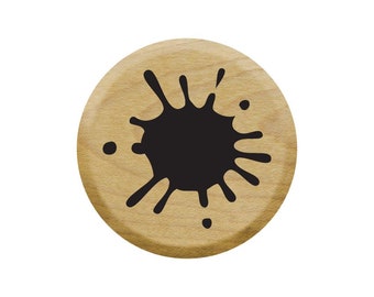 Op de afbeelding: Een ronde houten stempel met een zwart inktvlekontwerp.