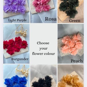 May include: A range of fabric flower embellishments in colours such as light purple, pink, green, red, peach, blue, black, and beige. Each flower is displayed on a textured square, with the colour name below. The text "Choose your flower colour" is in the centre.