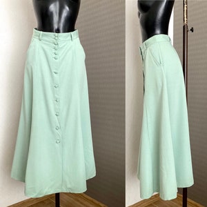 Può includere: Una gonna midi verde chiaro con bottoni sul davanti e una leggera forma a A.