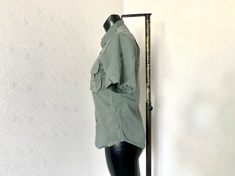Pu&ograve; includere: Una camicia a maniche corte di colore verde chiaro con bottoni e una tasca sul petto sinistro. La camicia &egrave; su un manichino e ha una vestibilit&agrave; rilassata.