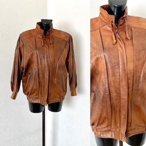May include: A brown leather bomber jacket with a zipper closure and a drawstring hood.