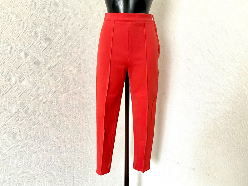 May include: A pair of coral red cropped pants with a high waist and a straight leg.